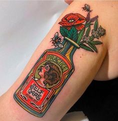 a woman's arm with a bottle and flowers on it