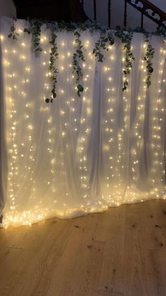 the curtain is covered with white lights and greenery on it's side,