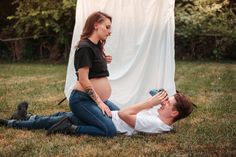 a woman is laying on the ground with a camera next to a man who is holding an electronic device