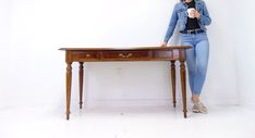 a woman sitting at a wooden table with a cell phone in her hand and looking at the camera