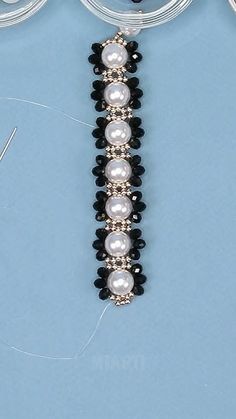 the beaded bracelet has pearls and black beads on it, along with two pairs of scissors