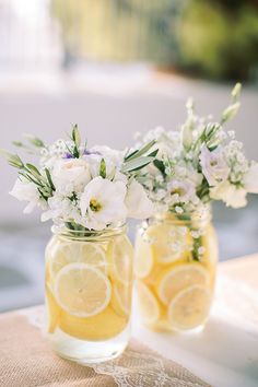 two mason jars filled with lemons and white flowers