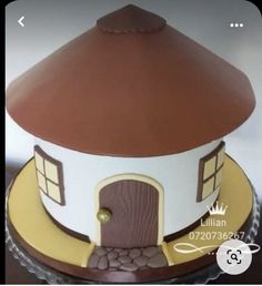 a cake with a brown and white house on it's side, sitting on top of a table