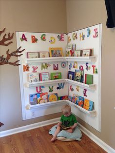 a child sitting on the floor in front of a book shelf