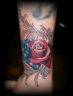 an american flag rose with feathers on the side of her leg, tattoo by person