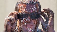 a man covered in sprinkles covering his face and hands with sunglasses on