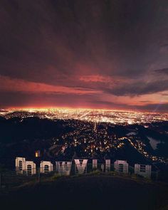 the words hollywood are lit up at night in front of a cityscape with lights