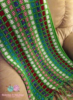 a crocheted blanket sitting on top of a couch