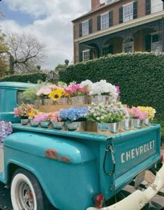 an old blue truck with flowers on the back