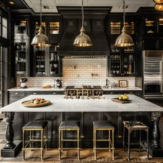 a large kitchen with black cabinets and gold pendant lights hanging from the ceiling over the island