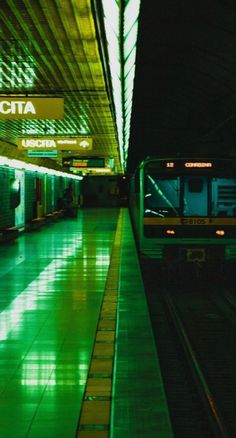 an empty subway station at night with green lights