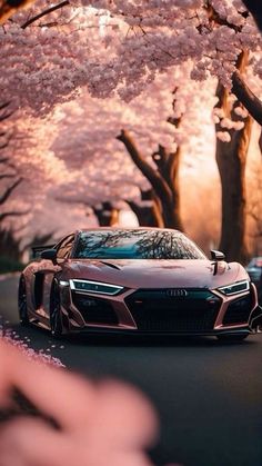 a car driving down the road with cherry blossom trees in the background