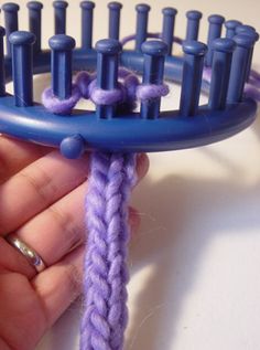 a person is holding a blue and purple comb with yarn on it's end