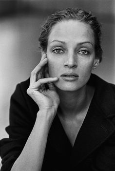 a black and white photo of a woman holding her hand to her face while looking at the camera