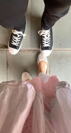 two people standing next to each other wearing tennis shoes and tulle skirt on the floor