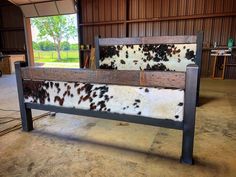 a bench made out of cow hides in a building with wood paneling and metal legs