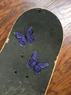 two purple butterflies on top of a skateboard