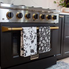 two towels hanging on the front of an oven with black and white florals in it