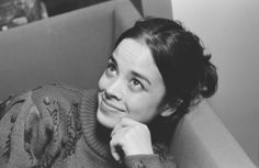 a black and white photo of a woman sitting on a couch with her hand under her chin