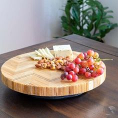 a wooden plate topped with grapes and cheese