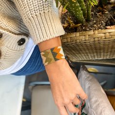 a woman wearing a bracelet with an orange and yellow design on it's wrist