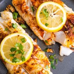 two pieces of fish with lemons and parsley