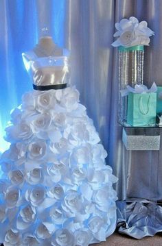 a dress made out of white flowers sitting on top of a table next to presents