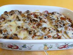 a casserole dish with cheese and mushrooms in it on a yellow counter top