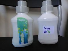 three bottles with labels on them sitting next to each other in front of a mirror