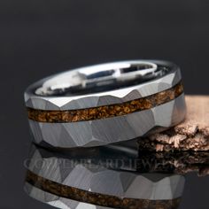 two wedding bands with wood inlays are shown on top of a piece of wood