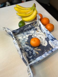 bananas, oranges and limes are sitting on a table with a blue floral tray