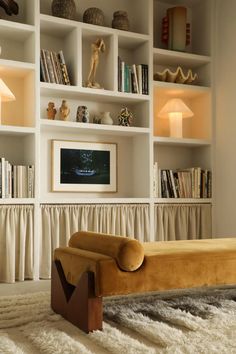 a living room filled with lots of white bookshelves next to a couch and lamp