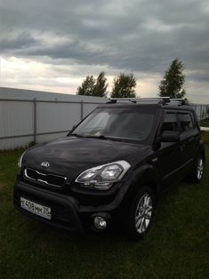 a black car parked in the grass near a fence