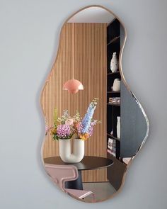 a mirror that has flowers in it and a vase on the table next to it