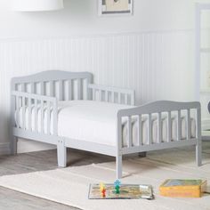 a baby's room with two white cribs and toys on the floor