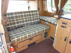 the inside of a camper with wood paneling and checkered fabric on it