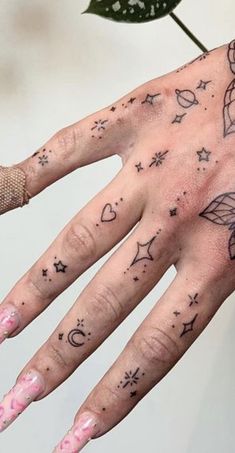 a woman's hand with tattoos on it and stars, planets, and hearts