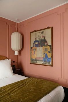 a bed in a room with pink walls and a painting on the wall above it