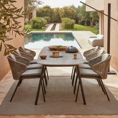 a dining table with chairs around it in front of an open patio area and swimming pool