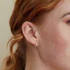 a close up of a person with red hair wearing ear piercings on their ears