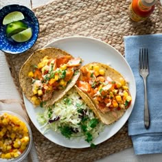 fish tacos with cole slaw and mango salsa on a plate next to a glass of orange juice