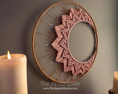 a pink doily hanging on the side of a wall next to a lit candle