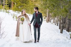 a bride and groom walking in the snow holding hands