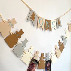 a baby's first birthday banner with teddy bears and one photo hanging on the wall