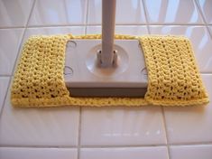 a yellow crocheted dishcloth is on top of a white electric scruber