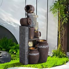 an outdoor fountain made out of pots and buckets in front of a wall with plants