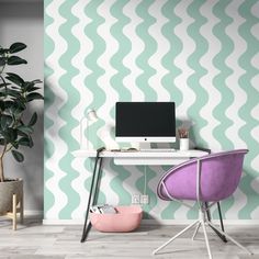 a desk with a computer on it next to a potted plant and wallpaper