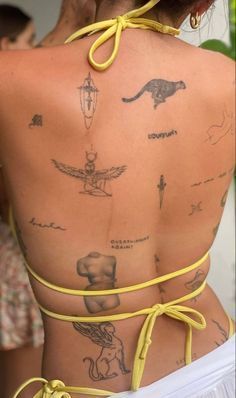 the back of a woman with tattoos on her body and yellow string around her neck