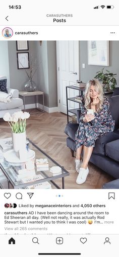 a woman sitting on top of a couch in a living room next to a coffee table