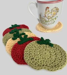 four crocheted coasters sitting next to a coffee cup